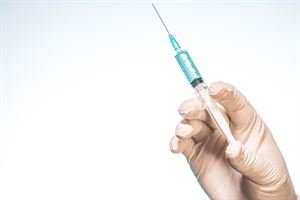 person-s-hand-wearing-surgical-glove-holding-syringe-with-white-background